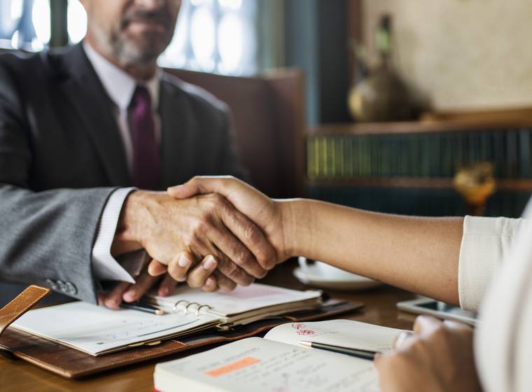 Attorney and client shaking hands across a desk